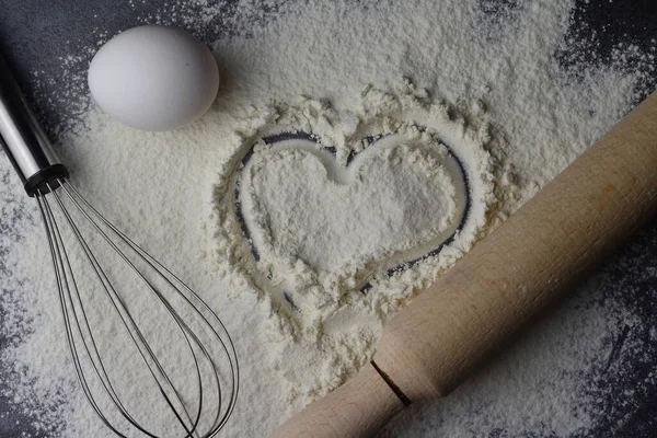 a heart is drawn on the sifted flour and a rolling pin next to it and