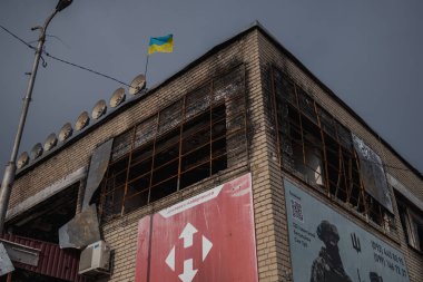 Izyum, Ukraine - November 10, 2023, the flag of Ukraine is installed on top of a burned-out building clipart