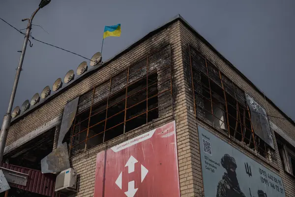 Izyum, Ukrayna - 10 Kasım 2023, Ukrayna bayrağı yanmış bir binanın tepesine asıldı