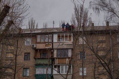 Kyiv, Ukrayna - 26 Kasım 2023: İnsansız hava aracı saldırısının ardından insanlar çatıyı onarıyor
