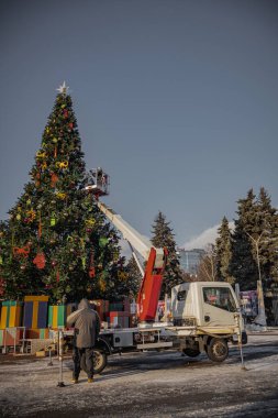 Kyiv, Ukrayna. 04.12.2023: asansörlü bir araba Noel ağacının yanında duruyor, işçiler dekore ediyor.