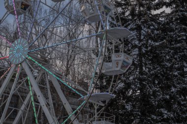 Kyiv, Ukrayna. 2023-12-04: Parlayan dönme dolap, arkasında karlı Noel ağaçları