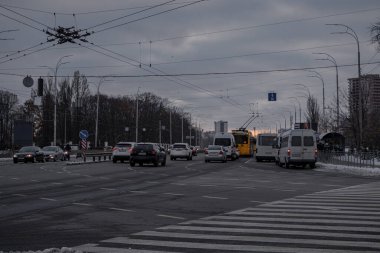 KYIV, UKRAINE - 6 ARALIK 2023 BULUŞLAR ayakta ve VDNG yakınlarındaki kar kaplı bir yoldan araçlar sürüyor.