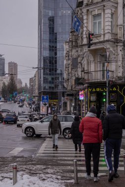 Kyiv, Ukrayna - 11 Aralık 2023: Gulliver İş Merkezi yakınlarındaki şehir merkezinde, insanlar öğle arasında öğle yemeğine gider, ve arabalar iş için oradan geçerler. Temizlikçiler karı temizler..