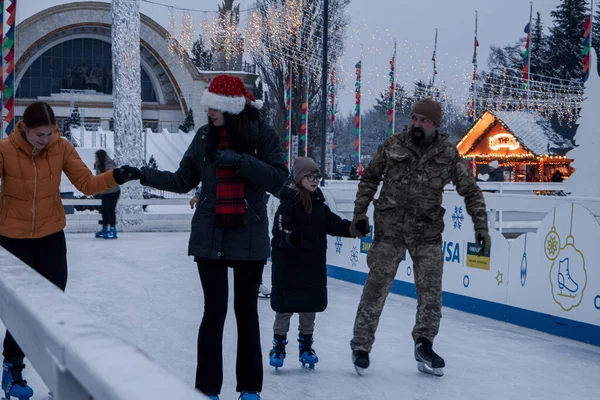 KYIV, UKRAINE - 12 Aralık 2023 İnsanlar iş gününden sonra dinlenmek ve buz patenine gitmek için Yeni Yıl Fuarı 'na geldi. Çocuklu ebeveynler soğuk havada ısınmak için sıcak içecekler içerler..