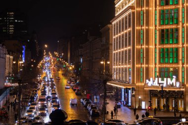 Kyiv, Ukrayna - 22 Aralık 2023: Khreschatyk 'teki Kyiv' in merkezinde Merkez Alışveriş Merkezi dekore edildi. Akşamları, çok güzel parlıyor. İnsanlar yürür ve arabalar yakınlarda sürerler. Bir sürü araba. Trafik sıkıştı