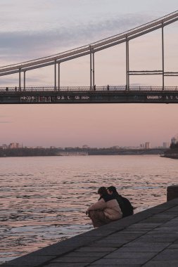 Kyiv, Ukrayna - 20 Aralık 2023: Noel 'den önce bir kış akşamı güzel bir günbatımı vardı. Dnipro 'nun setinde iki kişi oturuyor.
