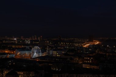 Kyiv, Ukrayna - 20 Aralık 2023: Akşam kenti. İnsanlar Podol 'daki Kyiv' in merkezindeki dönme dolaba biniyorlar. Şimdi parlıyor. İnsanlar buraya yürüyüşe geliyor..