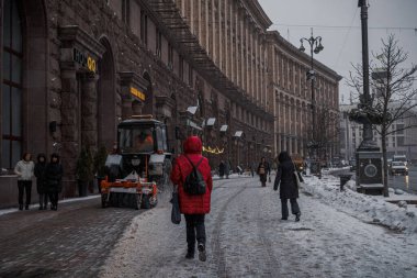 Kyiv, Ukrayna - 8 Aralık 2023: Sabah şiddetli kar yağıyordu ve temizlik ekipmanları şehre giriyordu. Ve insanlar karları temizliyor. Traktör yolu temizliyor. İnsanlar geçiyor.