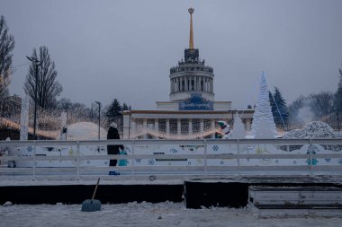 KYIV, UKRAINE - 12 Aralık 2023 İnsanlar iş gününden sonra dinlenmek ve buz patenine gitmek için Yeni Yıl Fuarı 'na geldi. Çocuklu ebeveynler soğuk havada ısınmak için sıcak içecekler içerler..