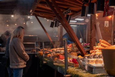 Kyiv, Ukrayna - 12 Aralık 2023: İnsanlar yeni yıl fuarına dinlenmek ve ızgarada taze yapılmış sokak yemekleri yemek için geldiler. Gerçek bir yiyecek ve içecek fuarı açıldı. İnsanlar sohbet eder ve dolaşır..
