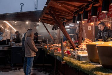 Kyiv, Ukrayna - 12 Aralık 2023: İnsanlar yeni yıl fuarına dinlenmek ve ızgarada taze yapılmış sokak yemekleri yemek için geldiler. Gerçek bir yiyecek ve içecek fuarı açıldı. İnsanlar sohbet eder ve dolaşır..