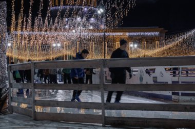 Kyiv, Ukrayna - 26 Aralık 2023: VDNG 'de her şey yeni yıl için dekore edildi. Bir sürü insanın kaydığı pistler ve buz pateni pistleri var. Üzerinde güzel, parlak çelenkler asılı.