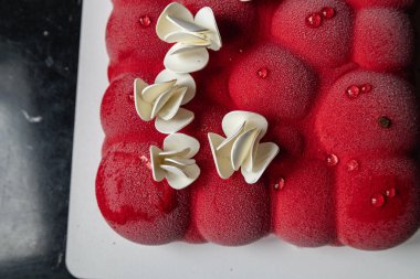 Kyiv, Ukrayna - 5 Şubat 2024 güzel mus, küçük toplar şeklinde kırmızı pasta. Üstünde beyaz çikolata çiçekleri var. Doğum günüm için bana pasta verdiler. Pasta siyah bir masanın üzerinde duruyor. lezzetli ahududu aromalı.