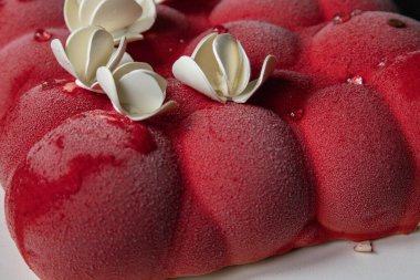 Kyiv, Ukrayna - 5 Şubat 2024 güzel mus, küçük toplar şeklinde kırmızı pasta. Üstünde beyaz çikolata çiçekleri var. Doğum günüm için bana pasta verdiler. Pasta siyah bir masanın üzerinde duruyor. lezzetli ahududu aromalı.