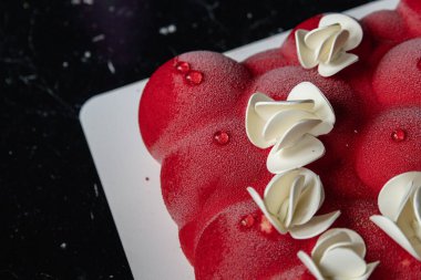 Kyiv, Ukrayna - 5 Şubat 2024 güzel mus, küçük toplar şeklinde kırmızı pasta. Üstünde beyaz çikolata çiçekleri var. Doğum günüm için bana pasta verdiler. Pasta siyah bir masanın üzerinde duruyor. lezzetli ahududu aromalı.