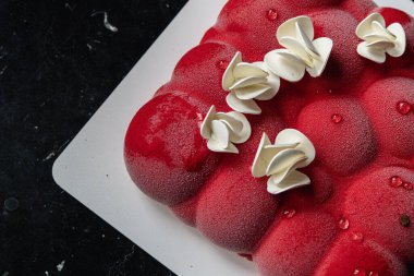 Kyiv, Ukrayna - 5 Şubat 2024 güzel mus, küçük toplar şeklinde kırmızı pasta. Üstünde beyaz çikolata çiçekleri var. Doğum günüm için bana pasta verdiler. Pasta siyah bir masanın üzerinde duruyor. lezzetli ahududu aromalı.