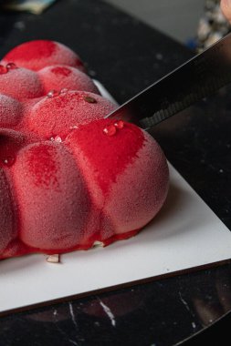 Kyiv, Ukrayna - 5 Şubat 2024 güzel mus, küçük toplar şeklinde kırmızı pasta. Üstünde beyaz çikolata çiçekleri var. Doğum günüm için bana pasta verdiler. Pasta siyah bir masanın üzerinde duruyor. lezzetli ahududu aromalı.