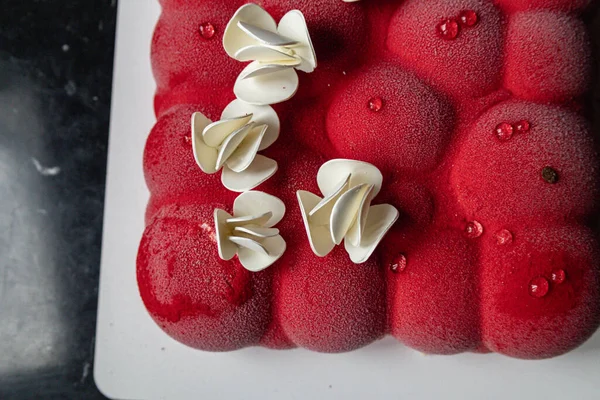 Kyiv, Ukrayna - 5 Şubat 2024 güzel mus, küçük toplar şeklinde kırmızı pasta. Üstünde beyaz çikolata çiçekleri var. Doğum günüm için bana pasta verdiler. Pasta siyah bir masanın üzerinde duruyor. lezzetli ahududu aromalı.