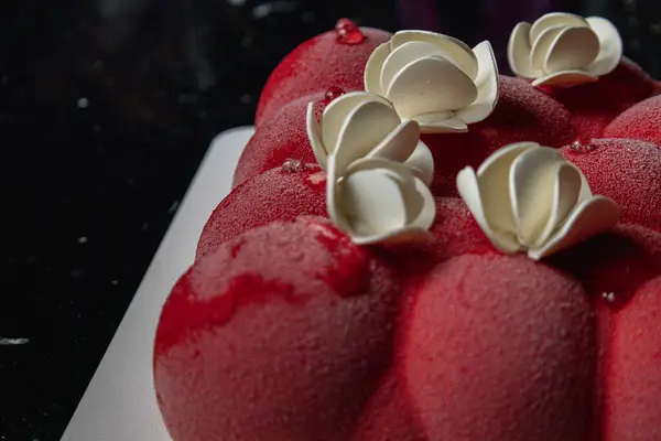 Kyiv, Ukrayna - 5 Şubat 2024 güzel mus, küçük toplar şeklinde kırmızı pasta. Üstünde beyaz çikolata çiçekleri var. Doğum günüm için bana pasta verdiler. Pasta siyah bir masanın üzerinde duruyor. lezzetli ahududu aromalı.