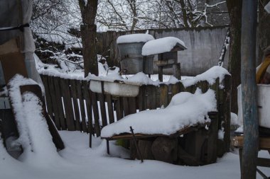 Kyiv, Ukrayna - 10 Şubat 2024. Büyükannemin köyünde karlı bir bahçe. Çatıdan sarkıtlar sarkıyor. Evin çatısında kar var. Bahçede bir kuyu var. Kapalı, su yok.