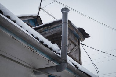 Kyiv, Ukrayna - 10 Şubat 2024. Büyükannemin köyünde karlı bir bahçe. Çatıdan sarkıtlar sarkıyor. Evin çatısında kar var. Sokakta karla kaplı kapalı bir kabuk. Kasvetli hava, gri gökyüzü