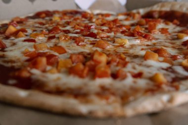 Kyiv, Ukrayna. 2 Mart 2024 'te, pizzacıdan kahvaltı için yeni yapılmış bir pizza karton bir kutunun içinde bir masada yatıyor. Peynirli pizza ve ince hamurlu kırmızı domates. Lezzetli ve sıcak.