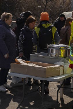 Kyiv, Ukrayna. 21 Mart 2024 sabahı erken saatlerde Ruslar şehre füze fırlattı. Hasarlı evler, arabalar ve yolda bir çukur. İnsanlar temizliğe yardım etmeye geldi..