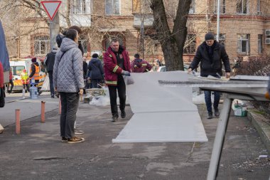 Kyiv, Ukrayna. 21 Mart 2024 sabahı erken saatlerde Ruslar şehre füze fırlattı. Hasarlı evler, arabalar ve yolda bir çukur. İnsanlar temizliğe yardım etmeye geldi..