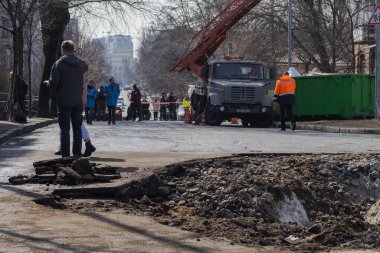 Kyiv, Ukrayna. 21 Mart 2024 sabahı erken saatlerde Ruslar şehre füze fırlattı. Hasarlı evler, arabalar ve yolda bir çukur. İnsanlar temizliğe yardım etmeye geldi..