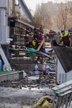 Kyiv, Ukrayna. 21 Mart 2024 sabahı erken saatlerde Ruslar şehre füze fırlattı. Hasarlı evler, arabalar ve yolda bir çukur. İnsanlar temizliğe yardım etmeye geldi..