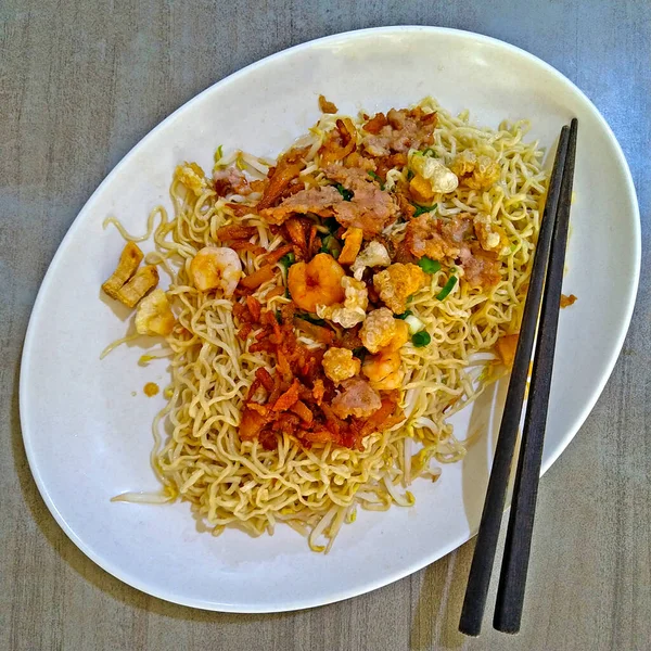 stock image Asian Curly Noodles sown with shrimp, pork, beef and chicken meats, on the oval white plate with black chopstick, with square size view.