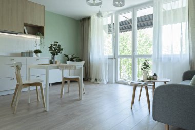 Ahşap zemin üzerinde pencere, kanepe, masa ve sandalyeler olan bir odanın tasarımı. Yeni dairede şık dekorları olan modern oturma odası.. 