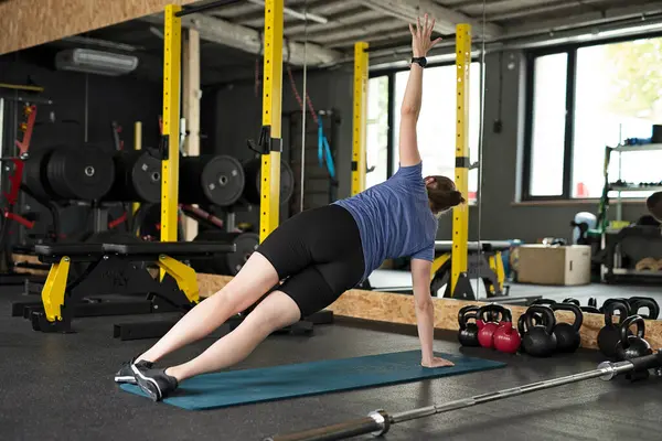 Full body woman on mat in a gym training crossfit in sportswear. Intense body building and  female workout.