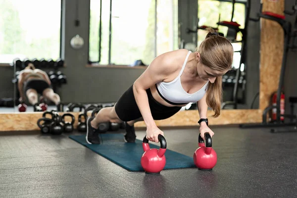 全身上下的女人女运动员在练跳板时 用沉重的哑铃垫在垫子上 女人在健身房锻炼 健康的生活方式 — 图库照片