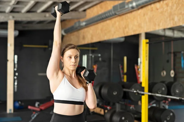 健身妇女穿着运动服在体育馆里训练肌肉 手握哑铃 锻炼和健康的生活方式概念 — 图库照片