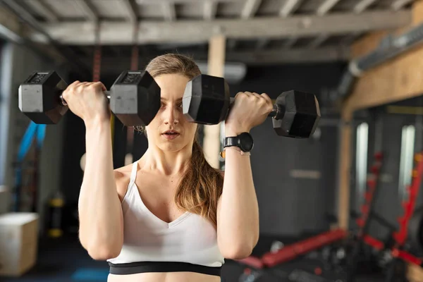 年轻的健身女子在体育馆用哑铃训练二头肌的肌肉 健康的生活方式 — 图库照片