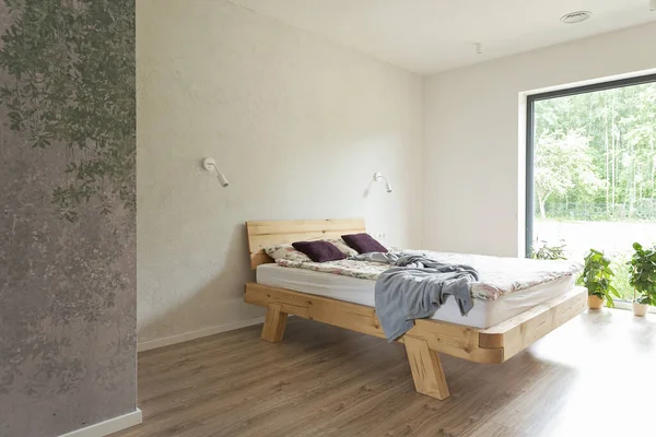 Minimalism in interior of bedroom with wooden double bed with window and wallpaper texture on the wall. Stylish design at home with window.