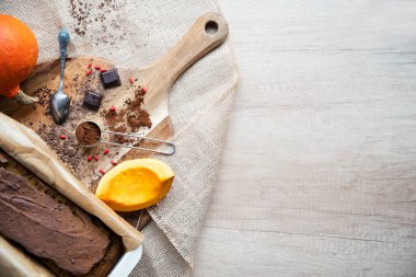 Kakaolu çikolatalı pasta, pudra kakao ve balkabağı. Kesme tahtasında pişirmek için sağlıklı iç malzemeler ve kopya alanı olan ahşap arkaplan.