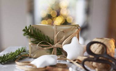 Kurdeleli hediye paketi ve noel yıldızı kurabiyeli köknar dalı. El yapımı dekorasyon. Yılbaşı hediyesi olarak klasik tasarım. Yaratıcı konsept. Bokeh arkaplanı.