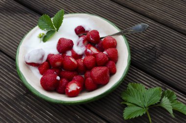 Tatlı olarak sağlıklı meyve, içinde krema var. Olgun kırmızı çilekler, lezzetli yiyecekler, doğal kahvaltı ve yazın bahçedeki en güzel yer. Kapat..