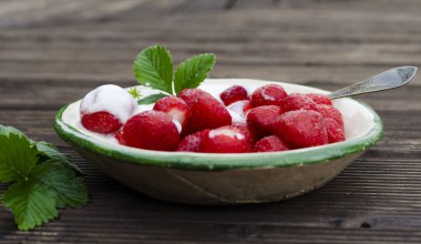 Taze taze olgun kırmızı çilek hasadı. Antika bir masada tatlı kremalı. Kahvaltıda sağlıklı yemek tatlısı. Meyveli yemek için kapayın..