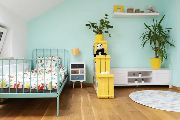 Room child in the attic in pastel color, carpet in modern design on the wooden floor and yellow furniture. Cozy interior for teenager with bed and shelf.