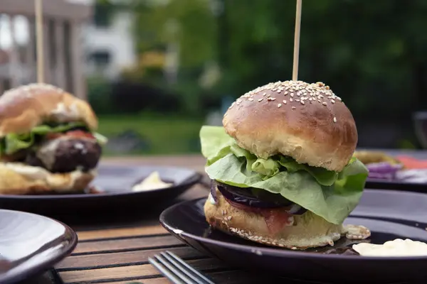 ハンバーガーは皿の上に バーベキューやグリル中に庭のテーブルで肉とレタスで自家製のバーガー アウトドアランチやディナー クローズアップ — ストック写真