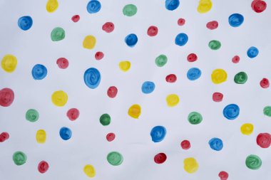 Beyaz kağıtta farklı renklerde noktalı arkaplan. Kırmızı, mavi, yeşil ve sarı noktalar çocuk tarafından boyanmış. Sanatsal ve yaratıcılık oyunu. Evde kal. Nokta dokusu.