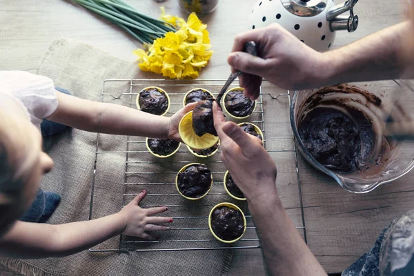 イースターのための健康的な自家製マフィンのための美味しいレシピ チョコレートデザートのペストリーを準備します イースターの前に焼く家族の時間 キッチンのテーブルに黄色い花が咲いています トップビュー — ストック写真