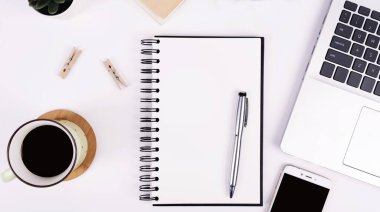 Bir fincan kahve, boş bir defter, boş ekranlı akıllı telefon ve beyaz mavi arka planda malzeme ofisi, üst manzara, günlük ofis hayatı. Üst görünüm