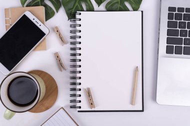 Boş defterli iş ve teknoloji ve model telefonlu telefon. Bir fincan kahve ve beyaz bir kitap kağıdıyla ofis masası. Düz nad üst görünüm yatıyordu.