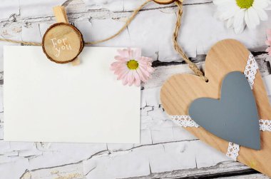 Anneler günü için tebrik kartı ya da ahşap arka planda asılı duran süsleme, çiçek ve kalp ile yabani otları ayıklama.