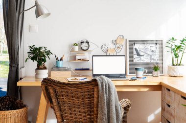 Tahta ofis masası, sandalye ve dizüstü bilgisayarla boş ekran ve maket. Ofis odası ve Coronavirus varken evde çalışmak. Masa ve aksesuarlar, kahve, telefon ve kalem. Çalışma alanı ve çalışma alanı.